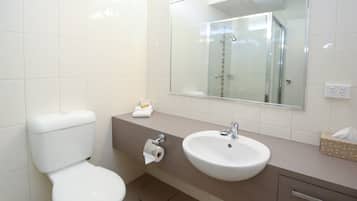 Un baño moderno con inodoro, lavamanos y espejo.
