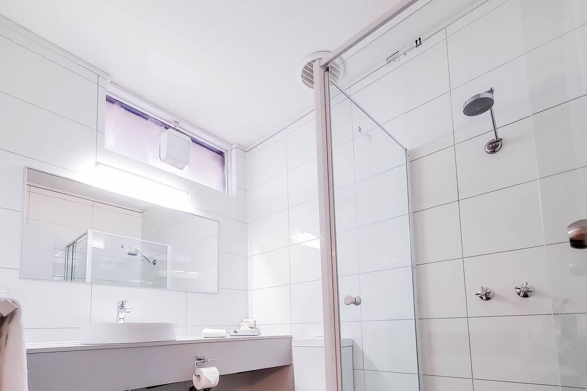Une salle de bain moderne avec une douche à parois de verre, un lavabo blanc et des toilettes.