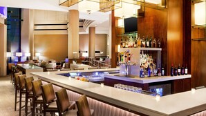 A bar area with a long counter, multiple bar stools, and a variety of liquor bottles. - The Westin Waltham-Boston (Waltham)