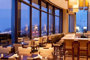 A modern restaurant with large windows, leather seating, and a bar area. - The Westin Waltham-Boston (Waltham)