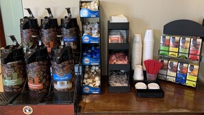 A coffee station with multiple coffee dispensers, a variety of coffee pods, and disposable cups. - Days Inn by Wyndham Las Vegas Airport Near the Strip (Las Vegas)
