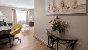 A modern living room with a dining area, a yellow chair, a glass table, and a painting of sailboats on the wall. - Days Inn by Wyndham Las Vegas Airport Near the Strip (Las Vegas)