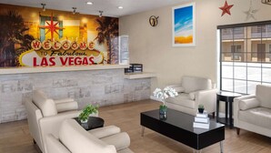 A hotel lobby with a reception desk displaying a 'Welcome to Fabulous Las Vegas' sign, a large window offering a view, and a seating area with sofas and a coffee table. - Days Inn by Wyndham Las Vegas Airport Near the Strip (Las Vegas)