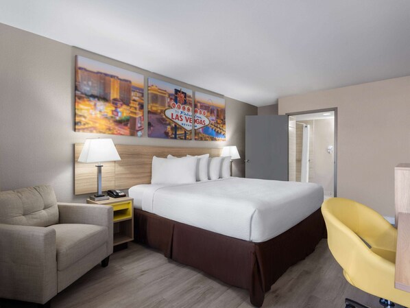 Una habitación de hotel con una cama, un escritorio, una silla y una pared con un cartel de Las Vegas.