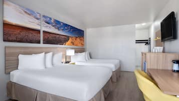 A hotel room with a large bed, two bedside tables, a desk with a chair, a flat-screen TV, and two wall-mounted paintings.