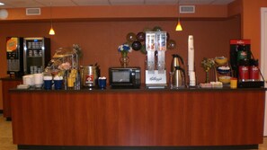 A hotel reception area with a wooden counter, a refrigerator, a coffee machine, a microwave, and various cups and containers. - Days Inn by Wyndham New Market/I-81 (New Market)