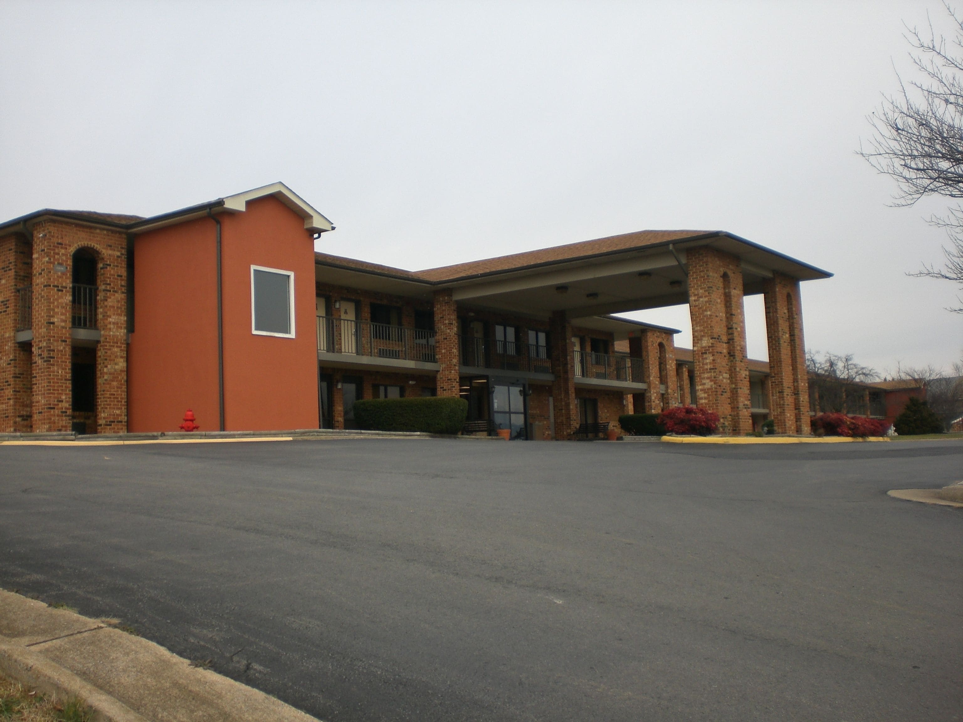 Un bâtiment à deux étages, doté d’une façade en briques, d’une entrée abritée et d’un parking.