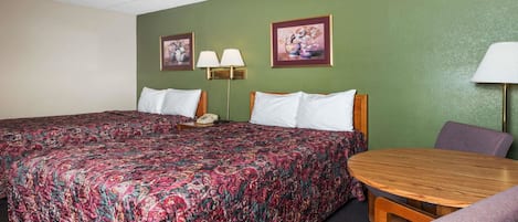 Quarto de hotel com uma cama grande, duas luminárias de cabeceira, uma mesa redonda de madeira e uma cadeira.