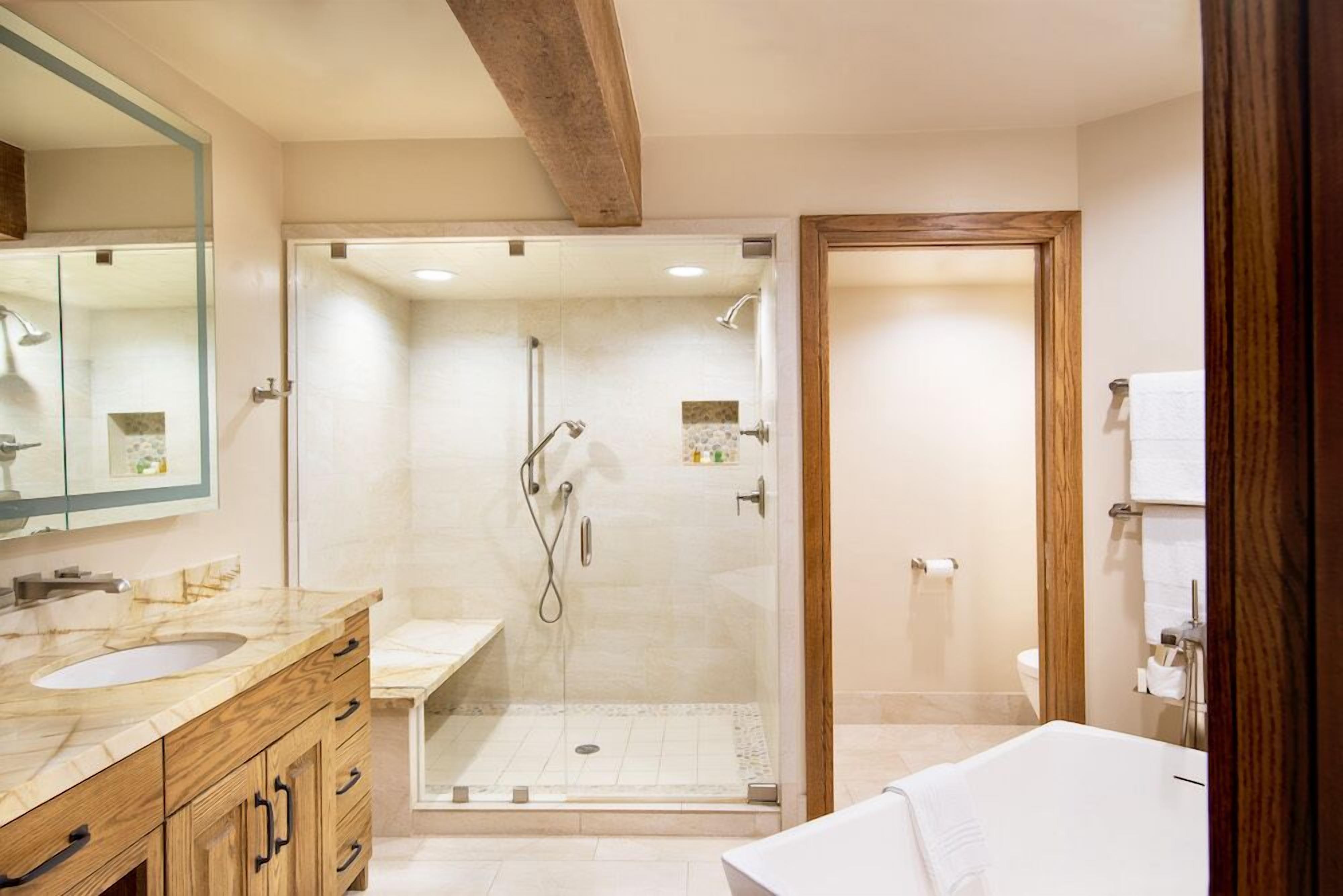 A modern bathroom with a glass-enclosed shower, a wooden vanity with a sink, and a large mirror.