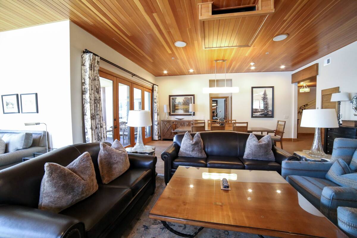 Ein geräumiges Wohnzimmer mit Ledersofas, einem Holztisch und einem Essbereich mit einer Chandelier.