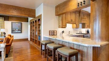 Una cocina moderna con armarios de madera, encimera de mármol y taburetes de bar.