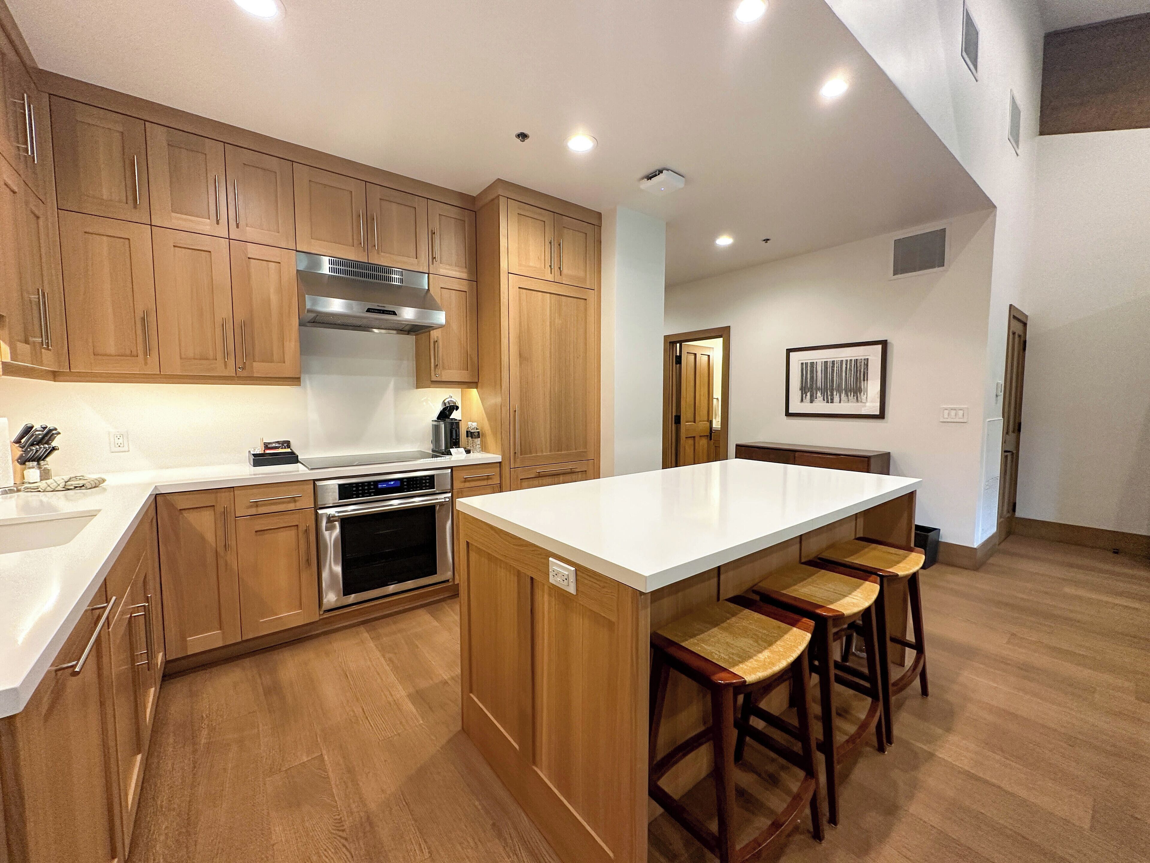A modern kitchen with wooden cabinets, stainless steel appliances, and a central island with bar stools.