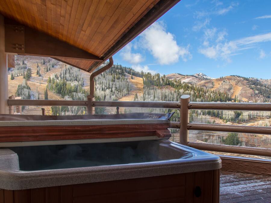 Ein Whirlpool auf einer Holzterrasse mit Blick auf eine gebirgige Landschaft.