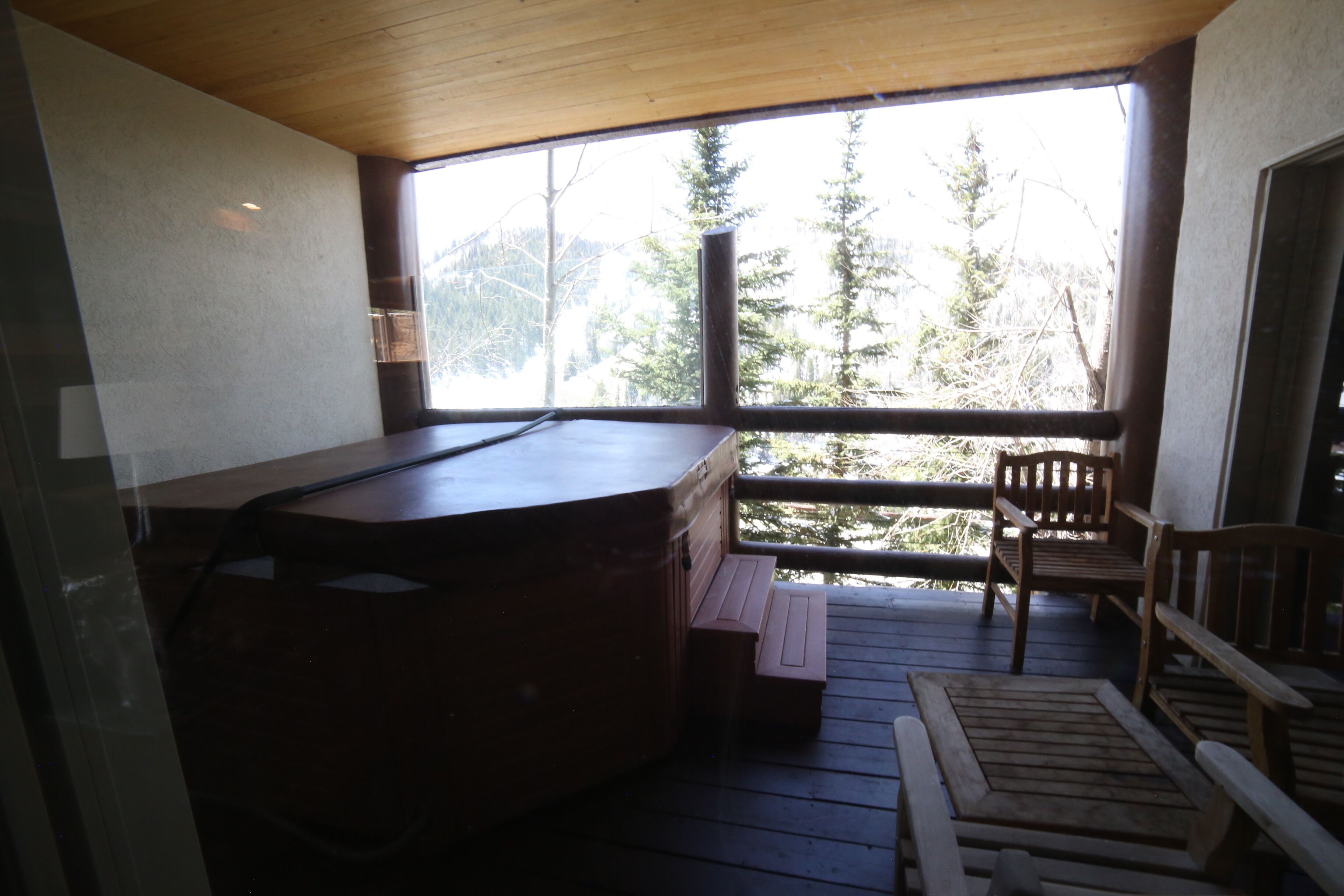 A hot tub on a wooden deck with a view of trees and mountains.