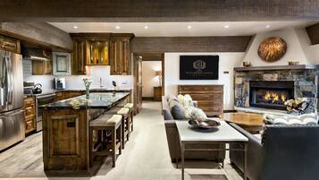 A modern kitchen with a central island, wooden cabinets, and a stone fireplace.