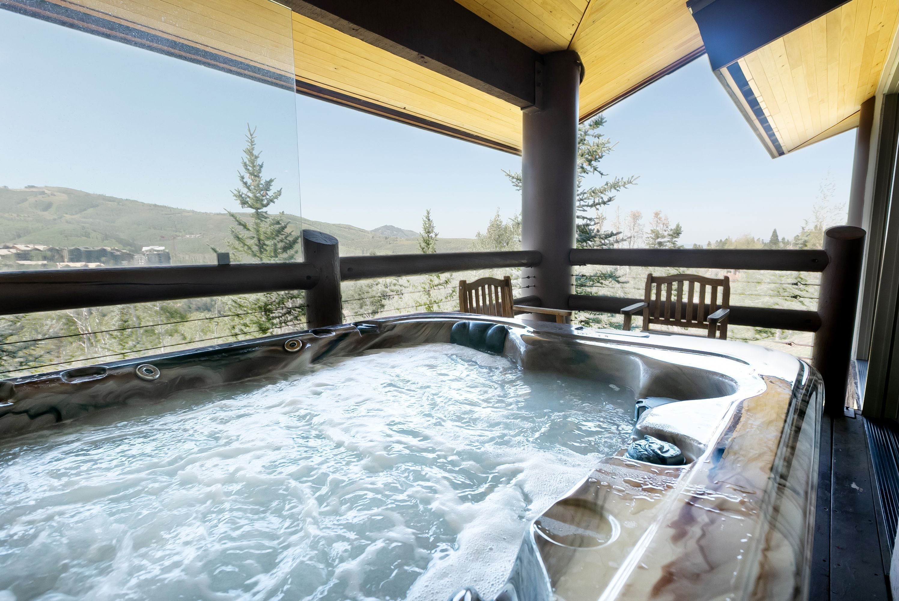 Un jacuzzi con terraza de madera y vistas del paisaje circundante.