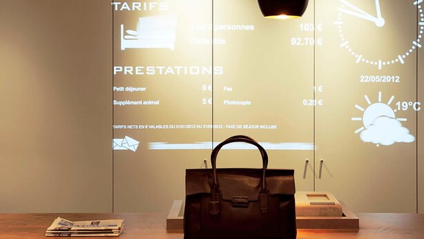 A reception area with a digital display listing reception tariffs and services, a clock, and a handbag on a table. - ibis Epinay sur seine Gennevilliers (Epinay-sur-Seine)