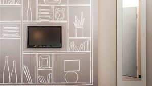A modern room with a flat-screen TV mounted on a wall with chalkboard-style drawings of various objects. - ibis Epinay sur seine Gennevilliers (Epinay-sur-Seine)