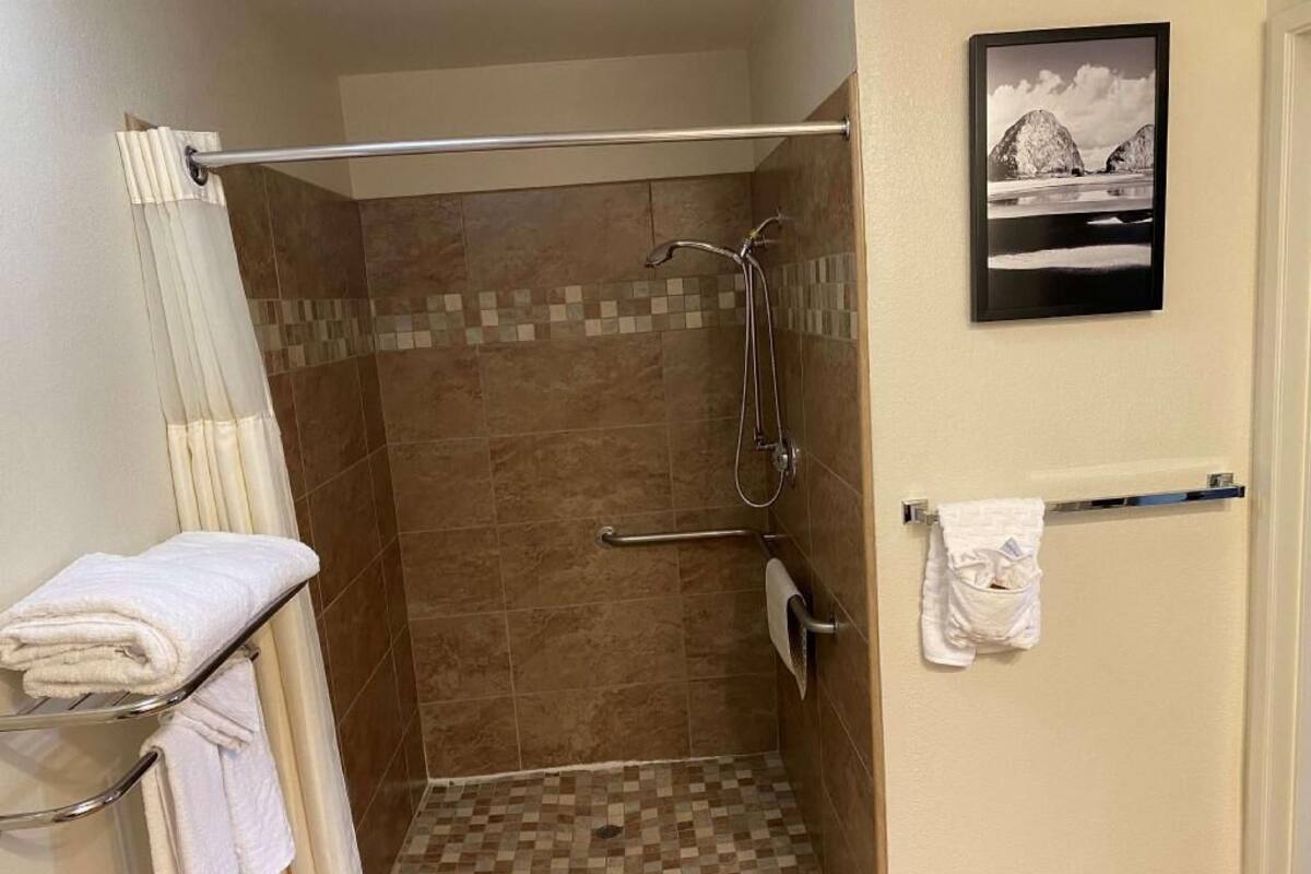 Une douche avec un sol carrelé, un porte-serviettes et un tableau encadré au mur.