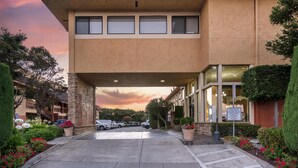 A hotel entrance with a covered parking area, a signboard, and a view of the surrounding buildings. - Best Western Plus Inn of Hayward (Hayward)