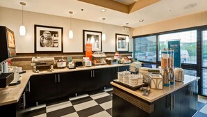 A modern kitchen area with a coffee station, including a coffee machine, milk frother, and various coffee containers.