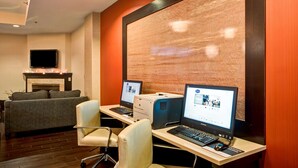 Habitació d'hotel amb una llar de foc, un sofà, dues escriptories amb ordinadors i una televisió.