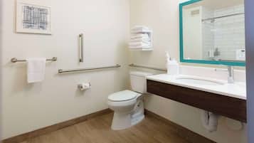 A modern bathroom with a toilet, sink, and handrails.