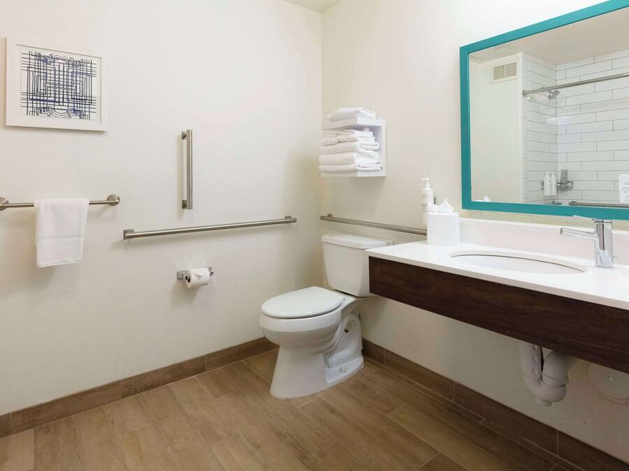 Un baño moderno con inodoro, lavamanos y barras de apoyo.