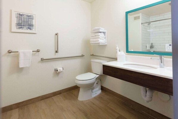 A modern bathroom with a toilet, sink, and handrails.