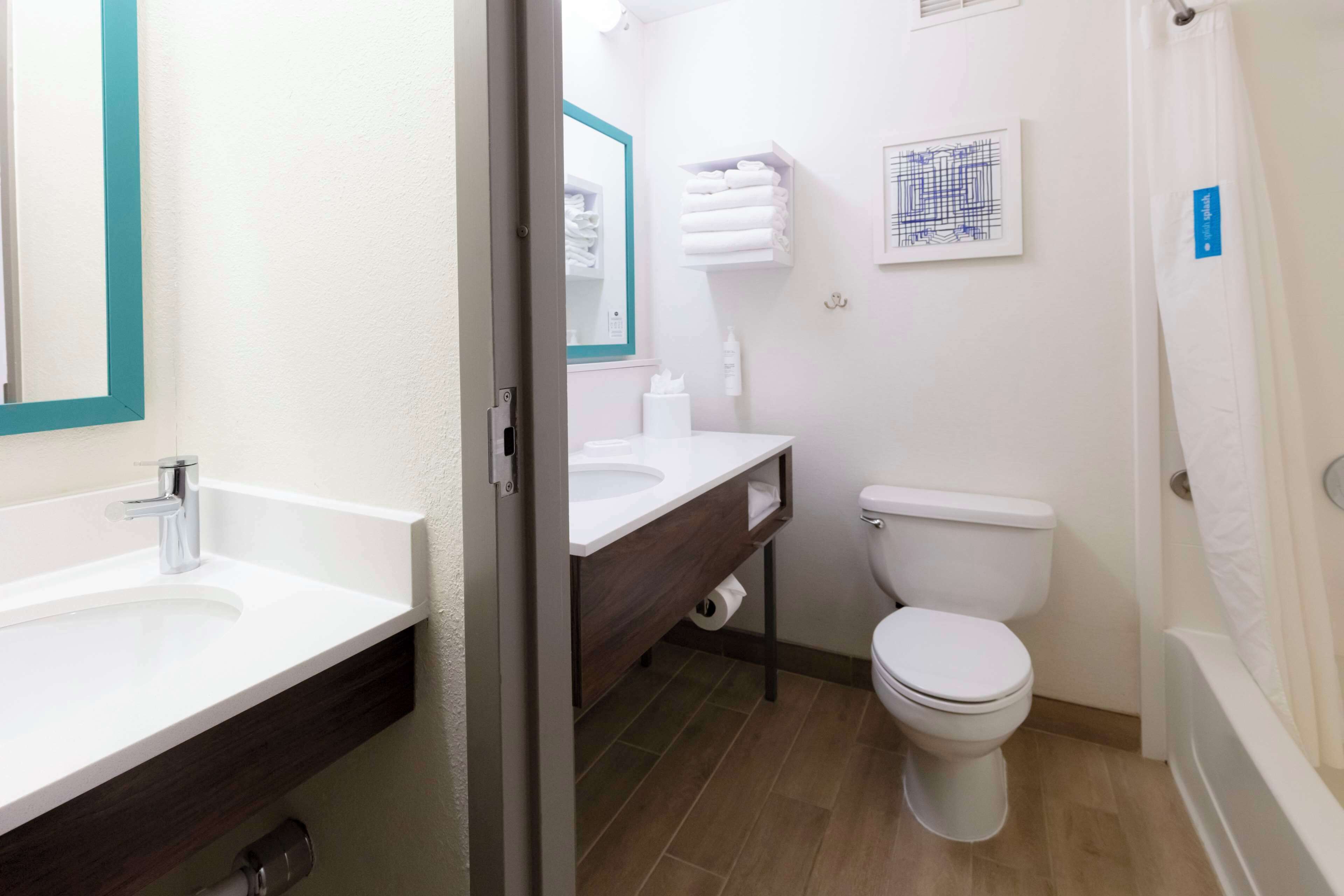 Een moderne badkamer met een wit wastafel, toilet en een bad.