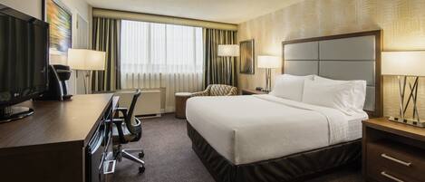 A hotel room with a bed, desk, chair, and TV.