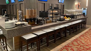 A modern breakfast bar with a long counter, multiple screens, and a variety of food options. - Holiday Inn Winnipeg South by IHG (Winnipeg)