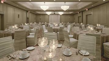 Un salón de banquetes con mesas redondas, sillas y candelabros.