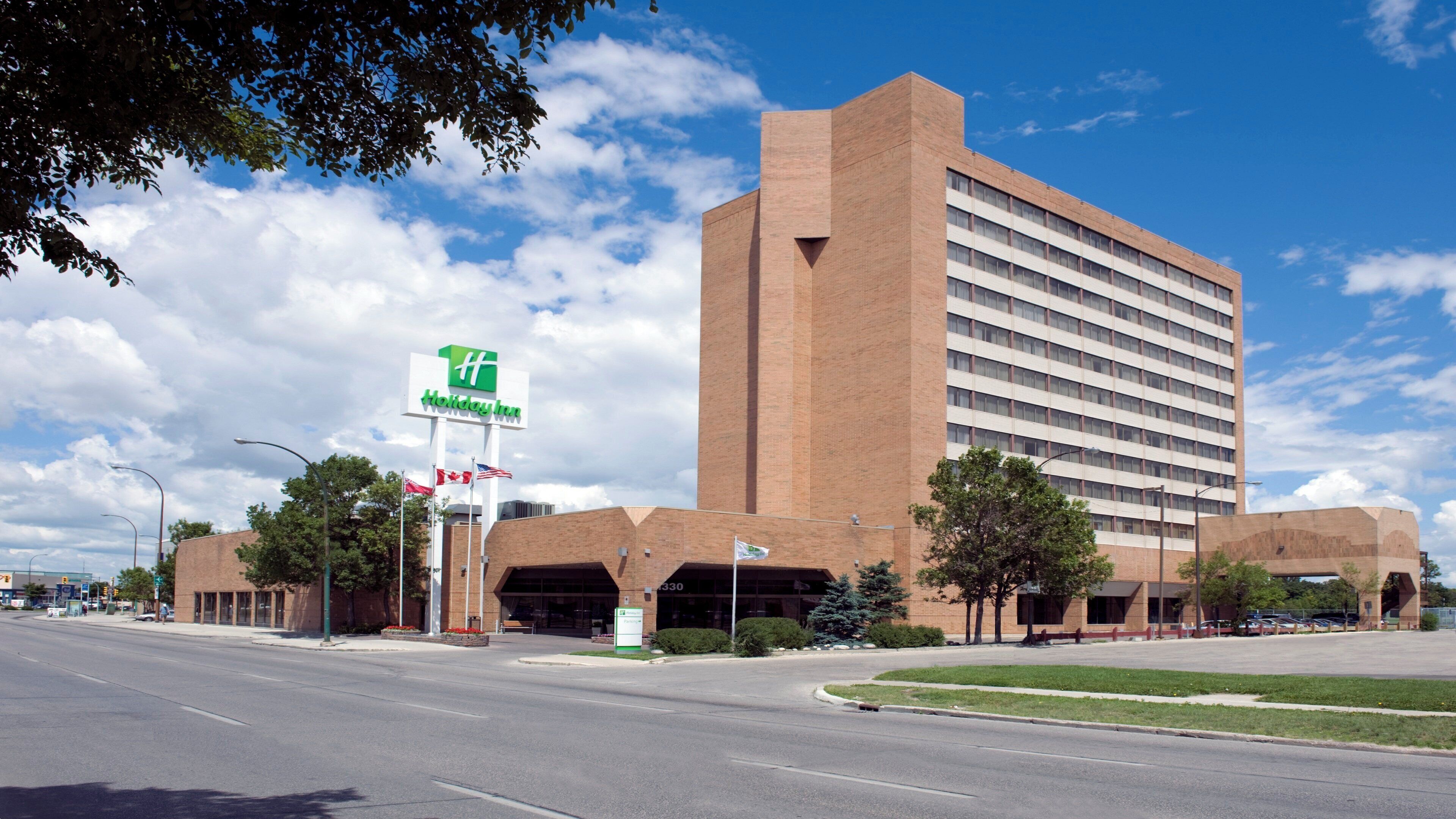 A Holiday Inn Express hotel with a brick facade, a large parking garage, and a clear sky.