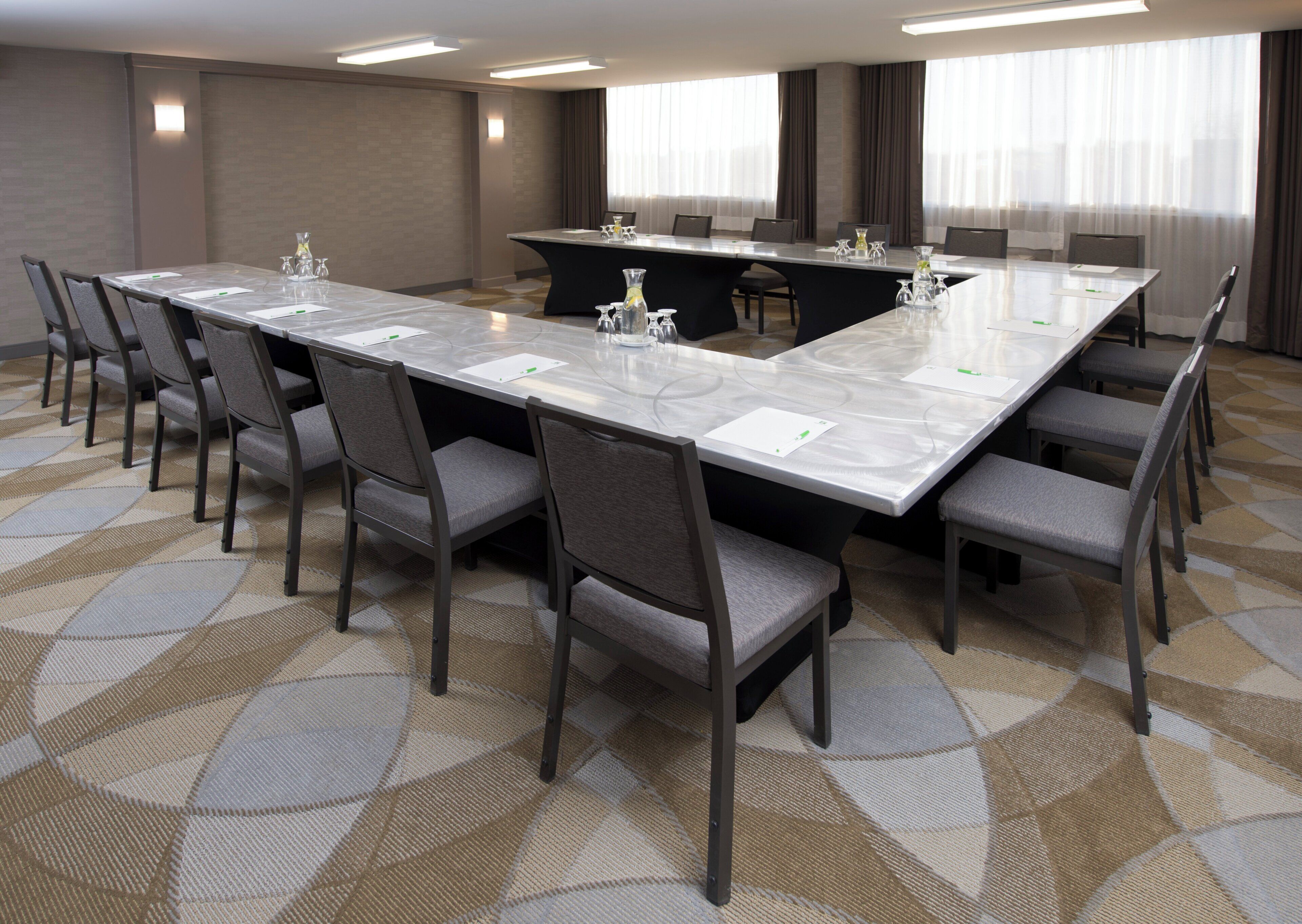 A conference room with a long table, multiple chairs, and a carpeted floor.
