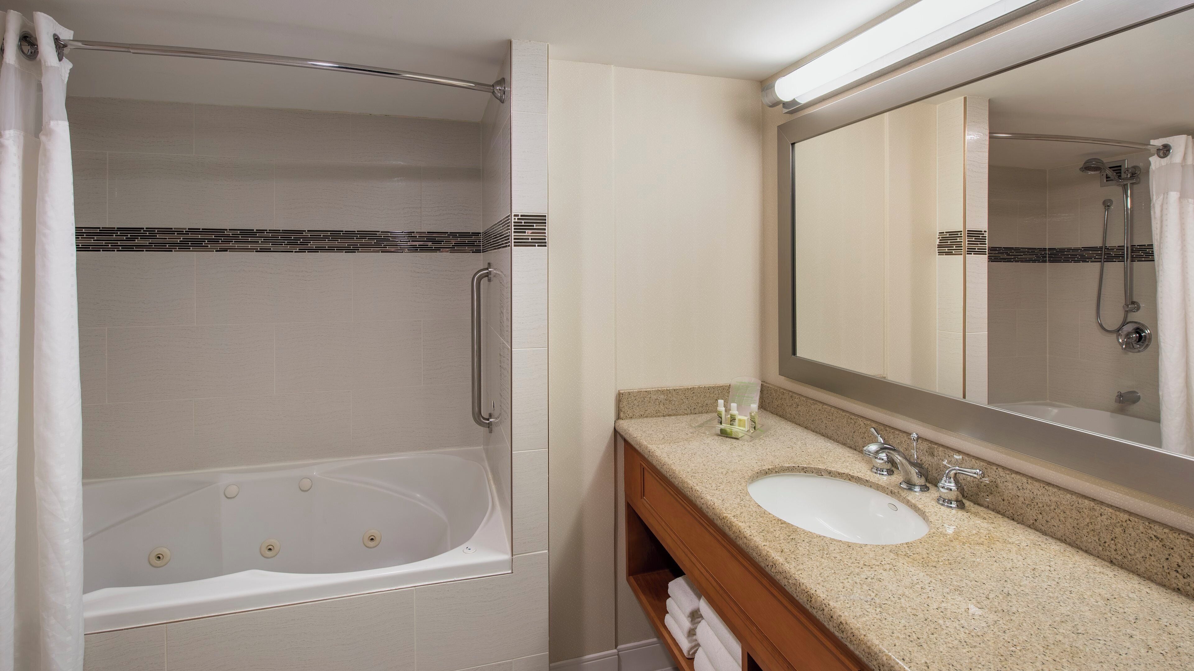 A bathroom with a bathtub, a sink, and a large mirror.