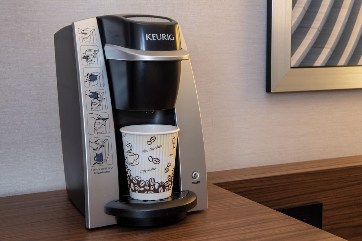 A Keurig coffee maker with a cup of coffee on the counter.