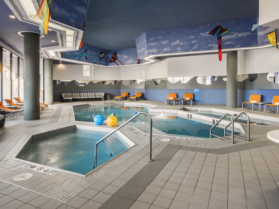 Una piscina interior con varias pistas, sillas de descanso y un techo con detalles decorativos.