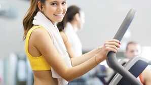 A person using an exercise machine in a gym with other people in the background. - Holiday Inn Winnipeg South by IHG (Winnipeg)