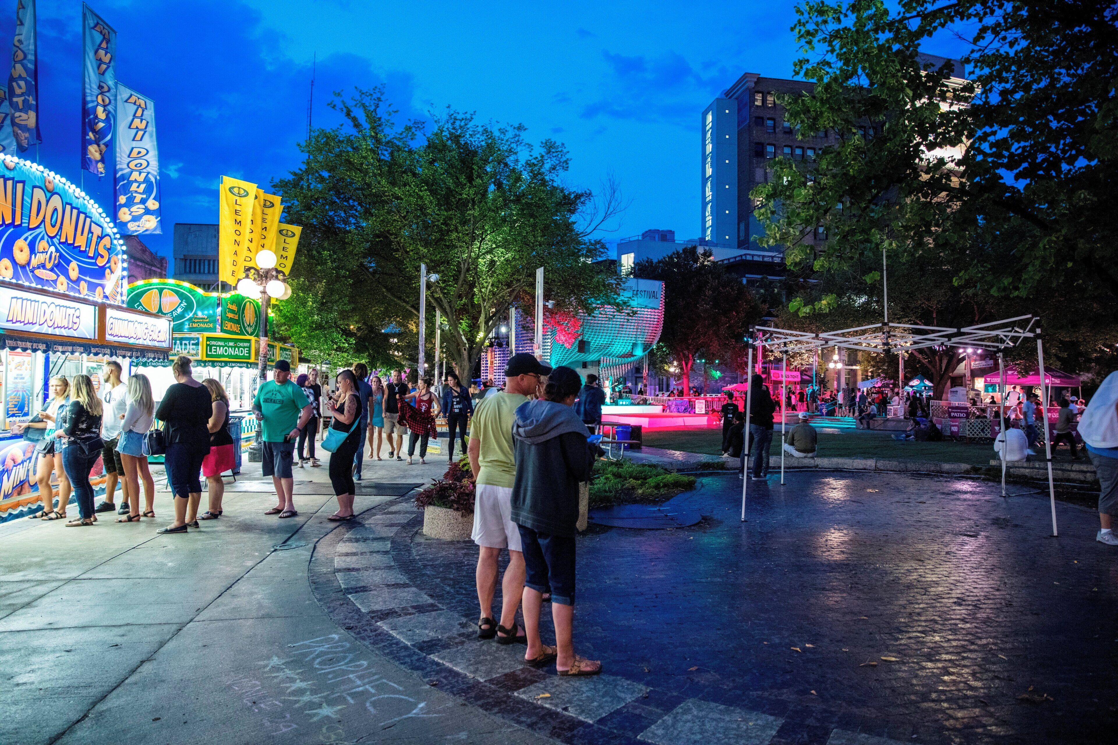 Una plaza pública con una fuente, árboles y gente.