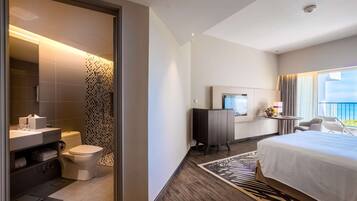 A hotel room with a large bed, a desk with a computer, a TV, and a view of the outdoors.