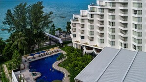 Ein Resort mit Schwimmbad, Meerblick und einem modernen Gebäude mit Balkonen.