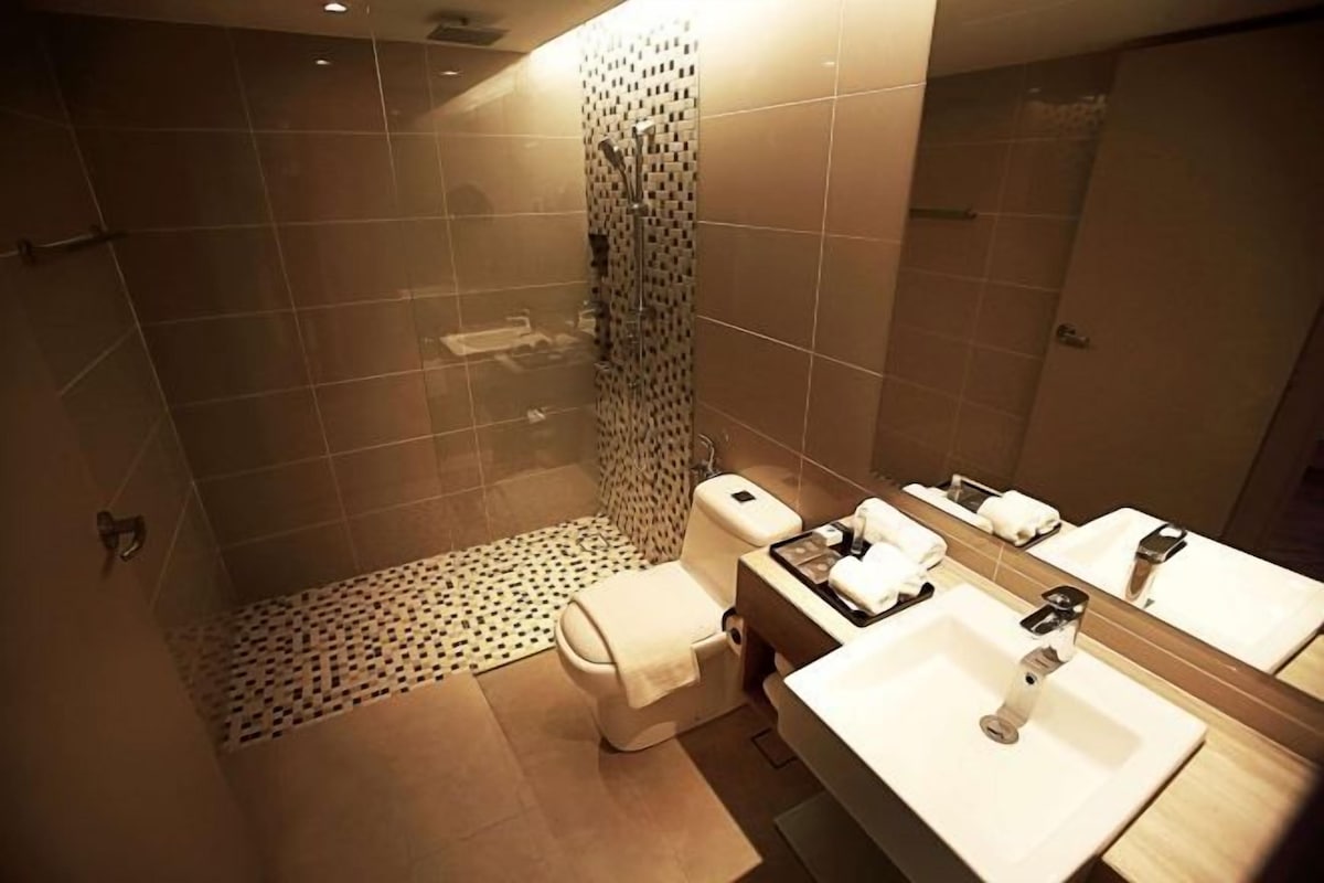 A modern bathroom with a shower, toilet, and dual sinks.