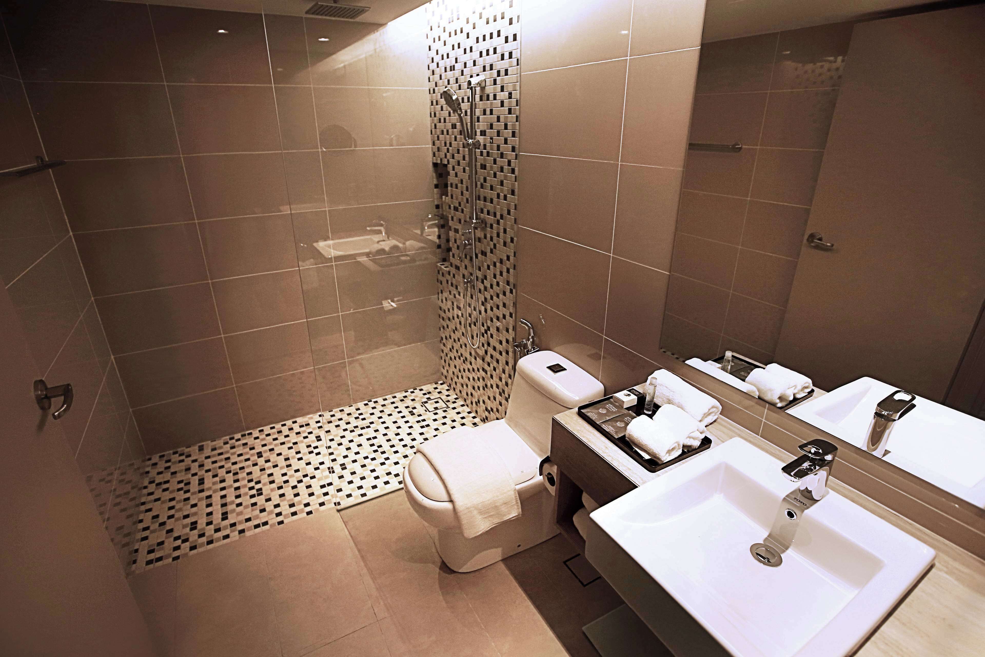 Un baño moderno con ducha, inodoro y dos lavamanos.