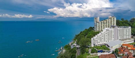 A coastal hotel with multiple high-rise buildings, a beachfront, and a clear view of the sea.