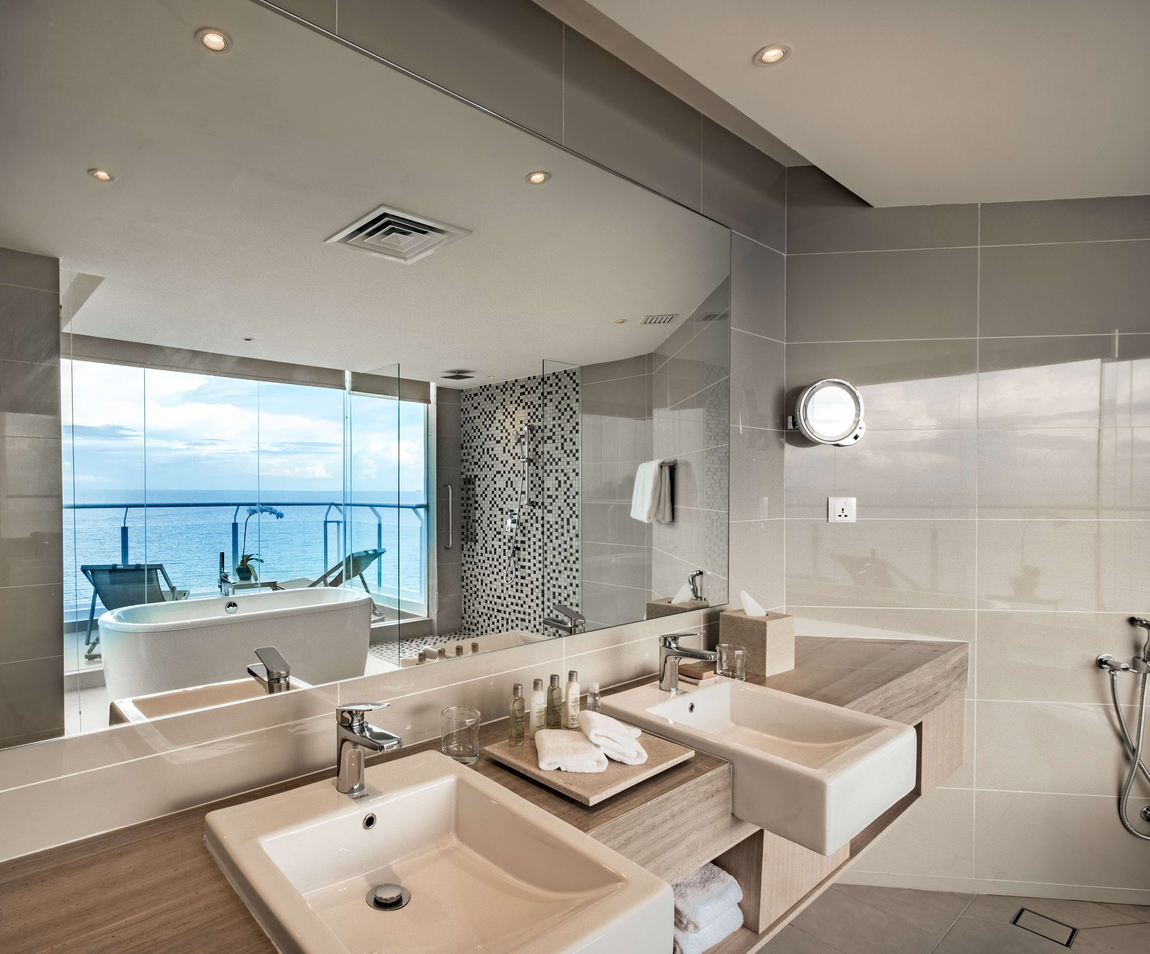 A modern bathroom with dual sinks, a large mirror, and a shower.