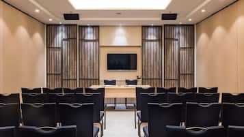 Une salle de conférence avec une longue table et des chaises, un téléviseur à écran plat et des panneaux de bois aux murs.