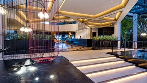 Eine moderne Lobby mit einem geometrischen Deckenmuster, einem Empfangstisch und einer Wasserspielelement.