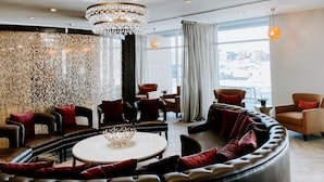 Un salon moderne avec un grand lustre, des canapés en cuir et une table basse ronde.