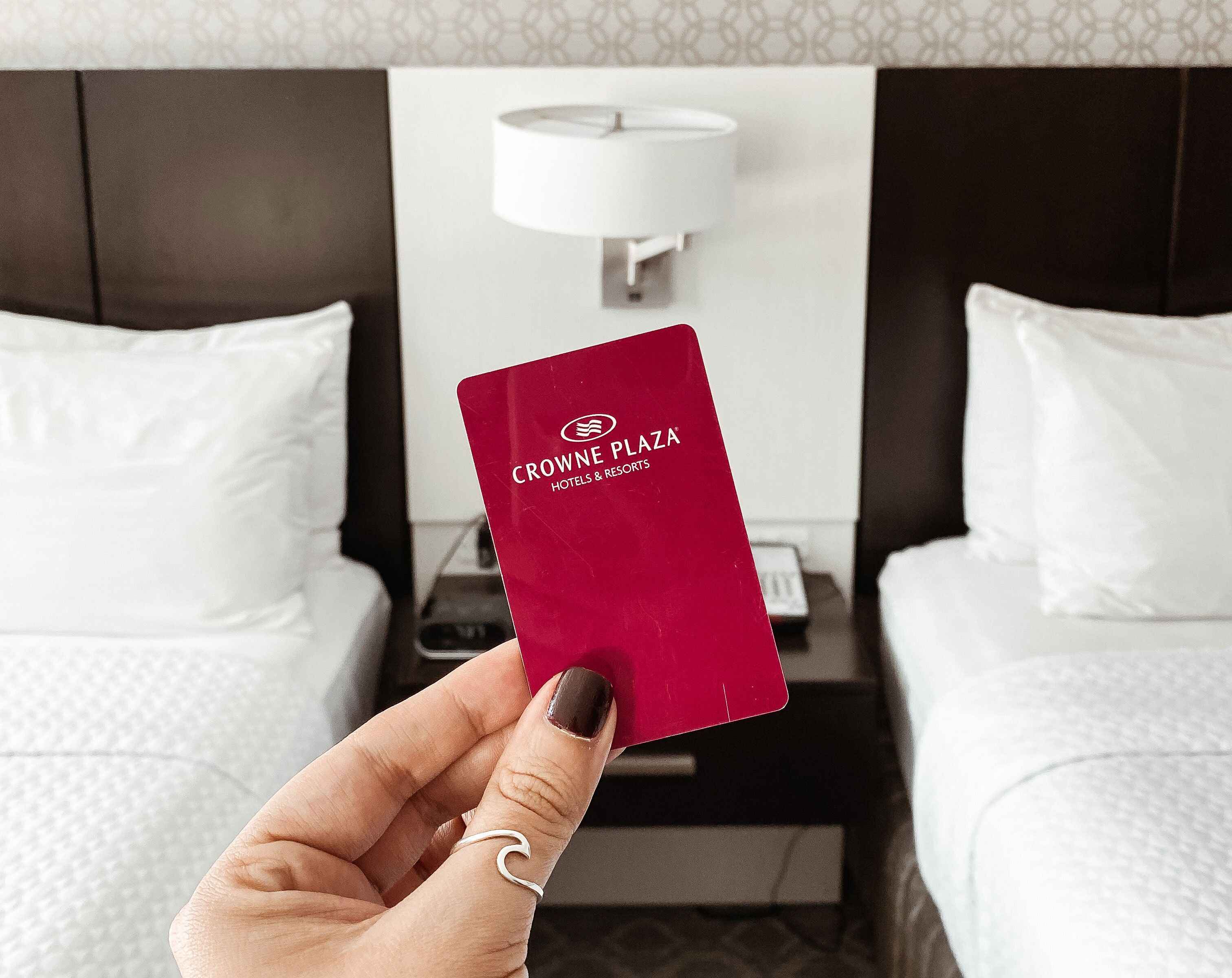 Uma mão segura um cartão vermelho dos hotéis Crowne Plaza Hotels & Resorts.